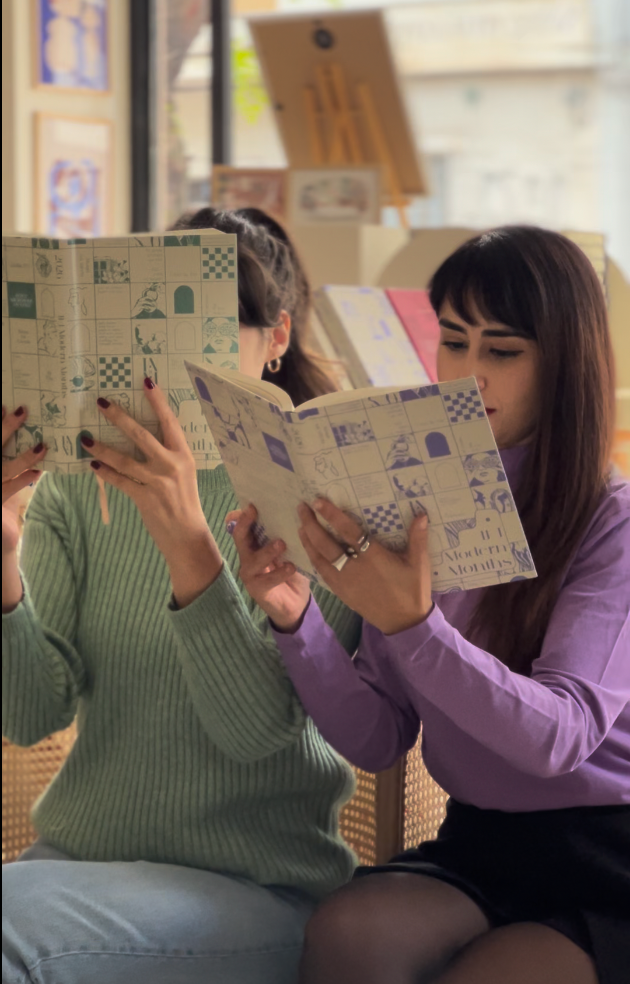 Two women reading planners with checkered covers in a casual setting.