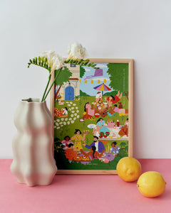 Framed colorful artwork of a picnic scene on a pink surface with a white vase and lemons.