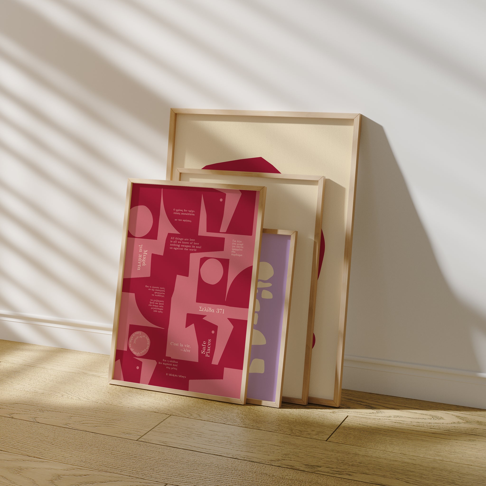 Stack of framed prints on a wooden floor with a light background