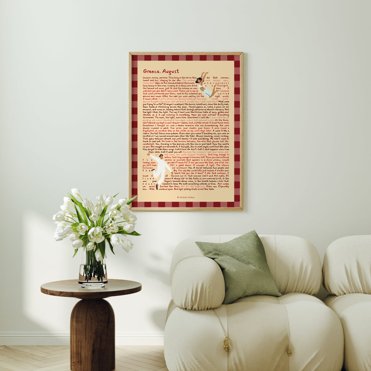 Framed artwork on a wall above a sofa with a small table and flowers.
